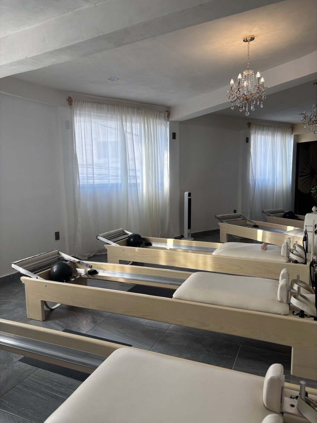 Camas reformer junto a cortinas de lino iluminadas por luz natural.