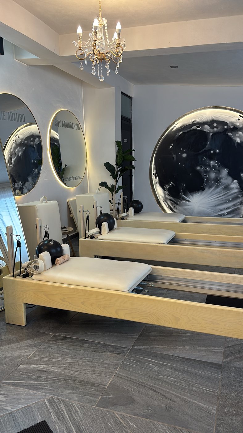Camas reformer frente a un mural circular de luna en tonos negros y blancos.